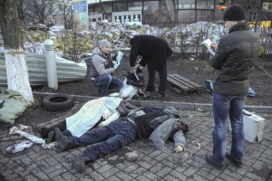 Полиция взгляд на трупы, лежащие на земле после столкновений между антиправительственными демонстрантами и сотрудниками службы безопасности, в центре Киева, 18 февраля 2014 года.