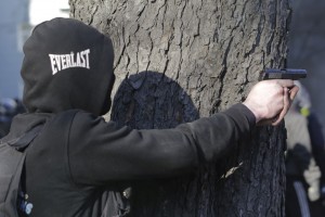 протестующий нацеливает пистолет во время столкновений с полицией в Киеве, 18 февраля 2014 года.