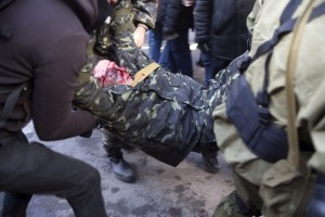 Демонстранты уносят раненого манифестанта, который пострадал во время столкновений между спецназом и антиправительственными манифестантами на Майдане Незалежности.