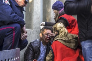 Женщина оказывает первую медицинскую помощь мужчине, который пострадал во время штурма пророссийскими демонстрантами здания областной администрации в Донецке 6 апреля 2014. 